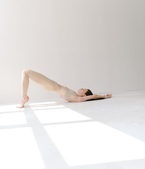Woman in a calm yoga pose in a studio with soft cyan light.